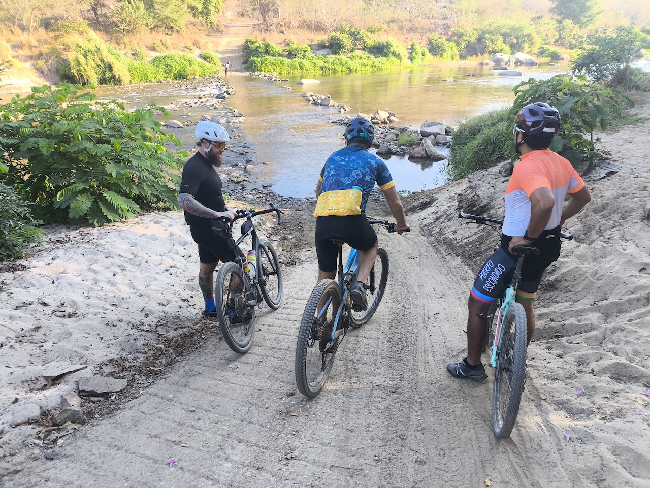 3 cyclists on a bike tour crossing a river.